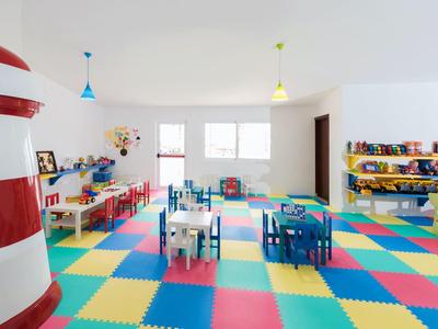 Bunter Kinderspielraum mit kleinen Tischen, Stühlen und weichem Bodenschutz aus Schaumstoffmatten.