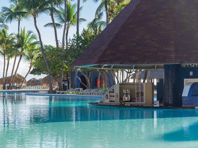 Swimmingpool mit Schwimmbartheke und Palmen im Hintergrund bei sonnigem Wetter.