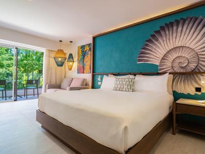 Camera d'hotel moderna con letto grande, parete blu e vista sulla terrazza con mobili da giardino.