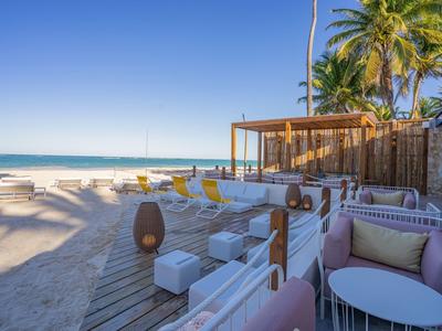 Strandlounge met witte sofa's, houten vloer en palmbomen onder een blauwe hemel