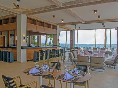 Moderner Hotel-Speiseraum mit Tischen, Barbereich und Meerblick durch große Fenster