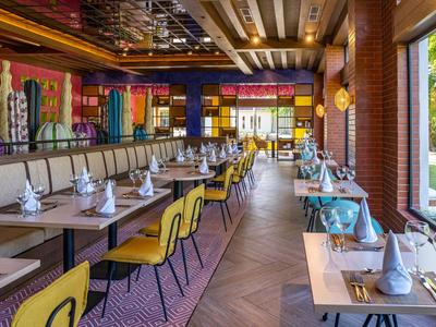 Modernes Restaurant mit bunten Stühlen und eleganten gedeckten Tischen bei Tageslicht.