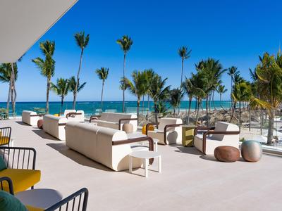 Moderner Außenbereich mit weißen Sofas und Palmen unter blauem Himmel am Meer