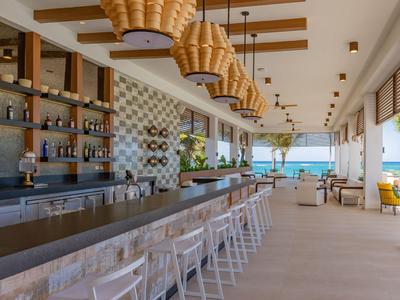 Moderner Hotelbarbereich mit Holzstühlen, Hängeleuchten und Meerblick