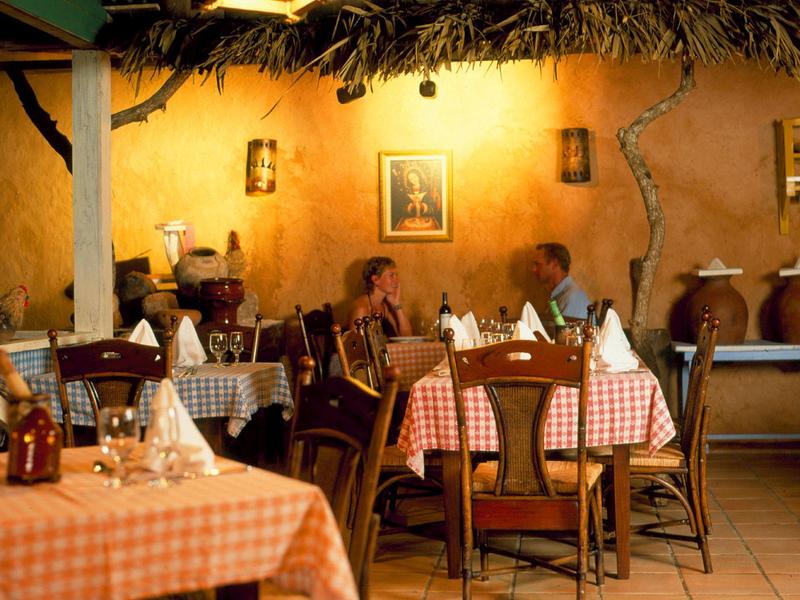 Ristorante accogliente con pareti arancioni, sedie di legno e tovaglie quadrettate rosse, illuminazione calda.
