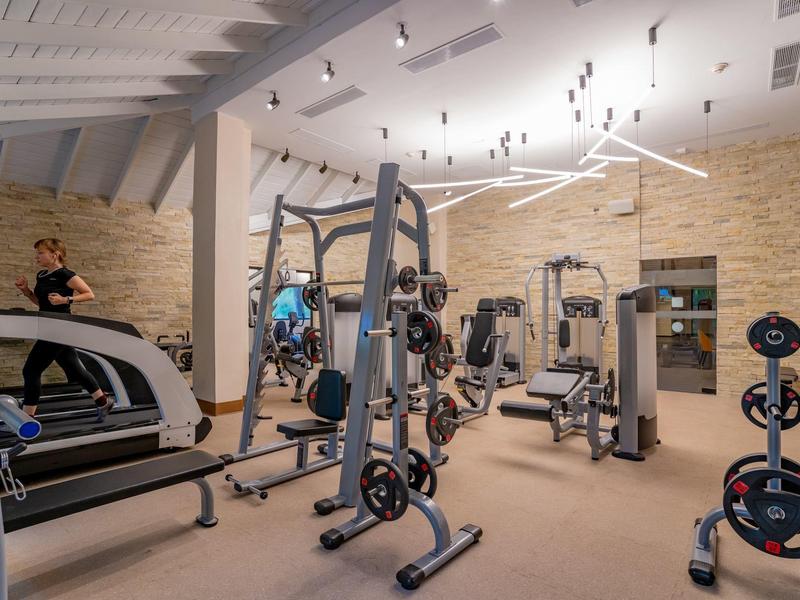 Palestra moderna dell'hotel con varie attrezzature per allenamento e una persona che corre sul tapis roulant.