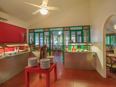 Interieur van een restaurant met buffet en eetgedeelte zichtbaar door groene glazen deuren