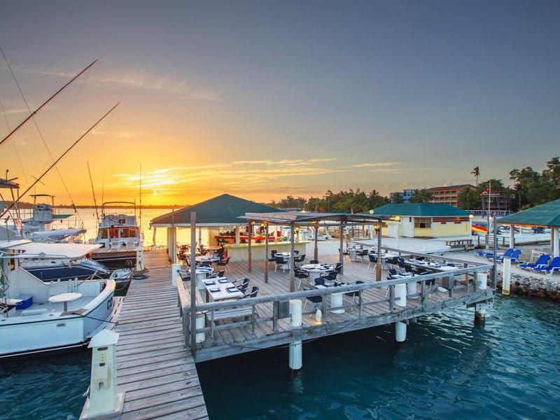 Zonsondergang boven een drukke jachthaven met steigers en boten.
