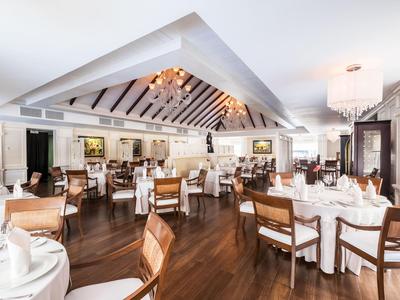 Interior de un elegante restaurante con manteles blancos y sillas de madera.