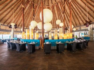 Velká kulatá restaurace s mnoha stoly pod doškovou střechou a kulatými světly