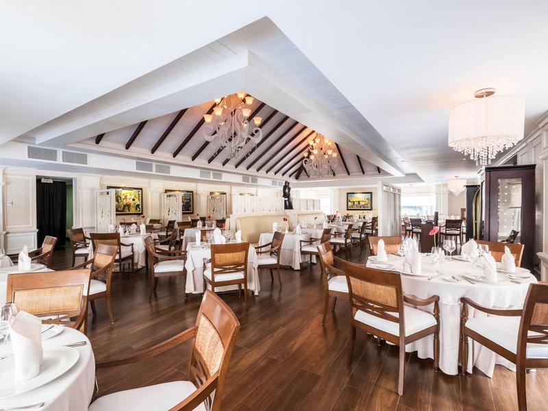 Elegantní restaurace s bílými ubrusy, dřevěnou podlahou a útulným osvětlením.