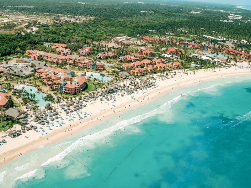 Luchtfoto van een strandresort met hotels, wit zand en turquoise zee.