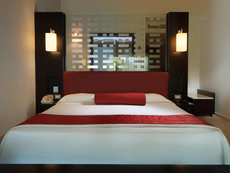 Moderne hotelkamer met groot bed, rood hoofdeinde en stijlvolle wandlampen