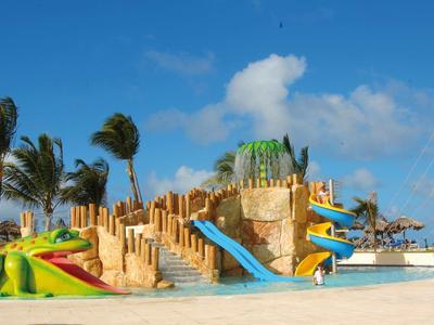 Colorful water playground with slides and palm trees on a sunny beach.