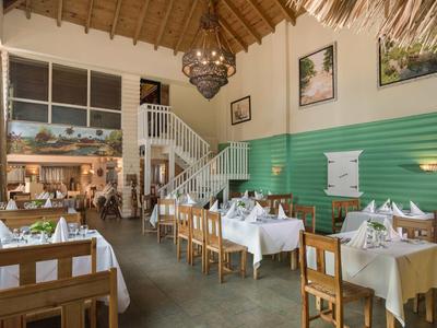 Cozy dining room with white-laid tables, wooden chairs, and high ceiling with chandelier.
