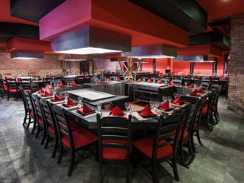 Modern dining area with red color scheme and grill stations in the center.