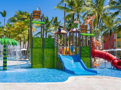 Kleurrijke waterspeeltuin met glijbanen en palmbomen in een tropisch resort.