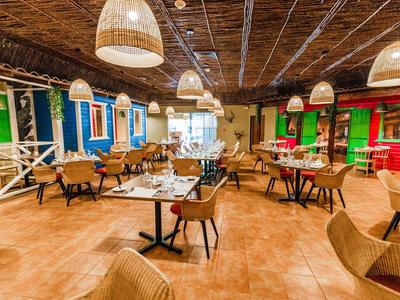 Interieur van een kleurrijk restaurant met houten tafels, rieten stoelen en decoratieve lampen