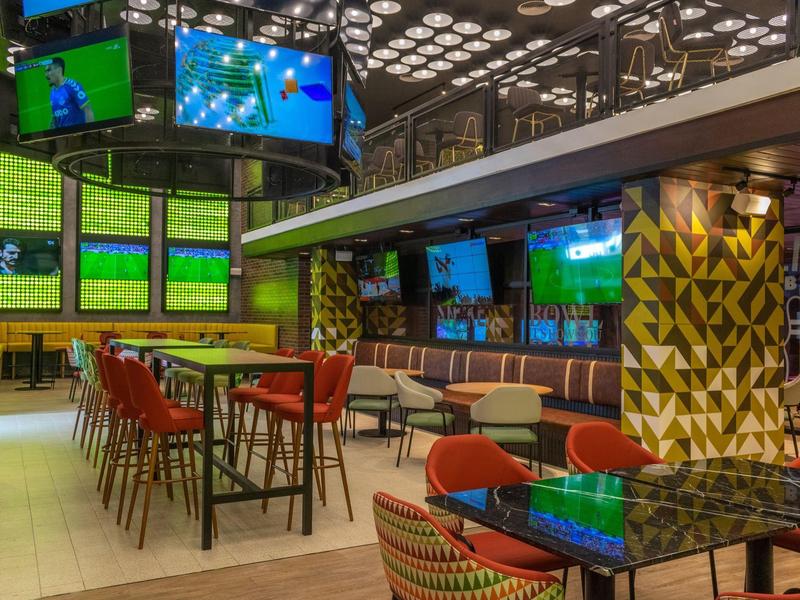 Moderne sportbar met meerdere schermen en kleurrijke zitplaatsen.