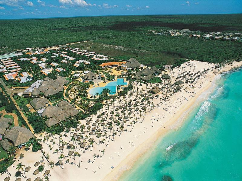 Vue aérienne d'une station avec piscine, plage et mer turquoise le long de la côte.