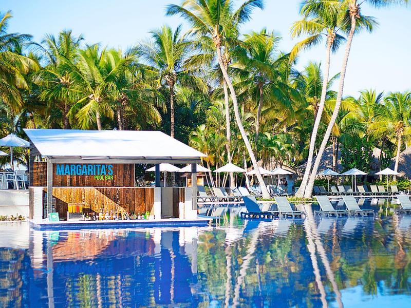 Piscine avec une cabane et des palmiers en arrière-plan par une journée ensoleillée