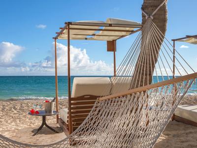 Hamac confortable et chaise longue sur la plage avec vue sur la mer sous un ciel clair.