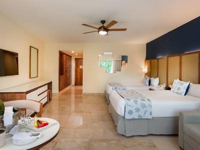 Modernes Hotelzimmer mit zwei Betten, Holzmöbeln und Deckenventilator.