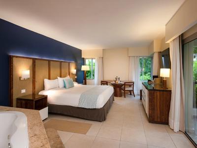 Modernes Hotelzimmer mit großem Bett, Sitzbereich und Blick auf Garten