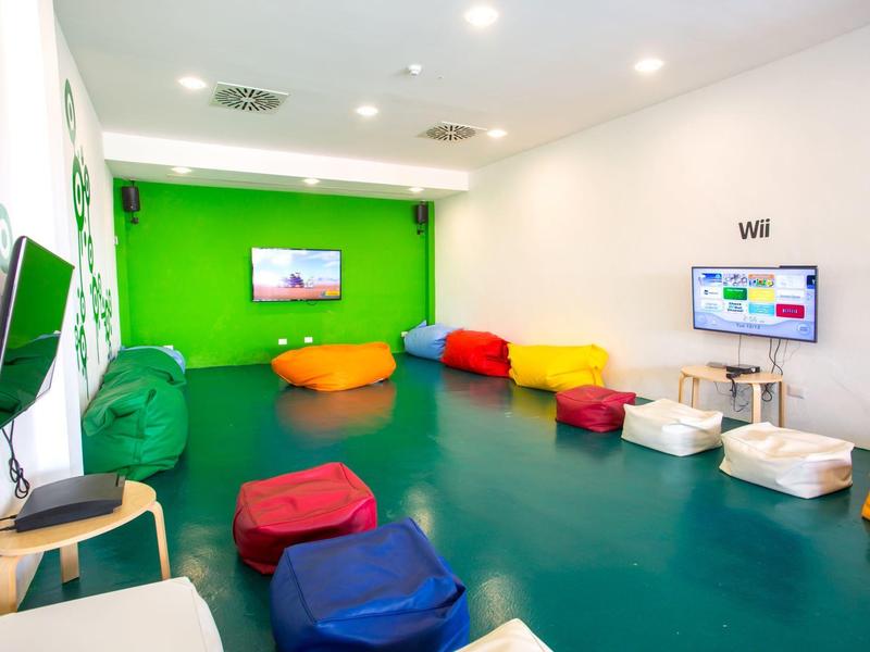 Bunter Spielraum mit Sitzsäcken, Fernsehern und Konsolen für Freizeitaktivitäten.