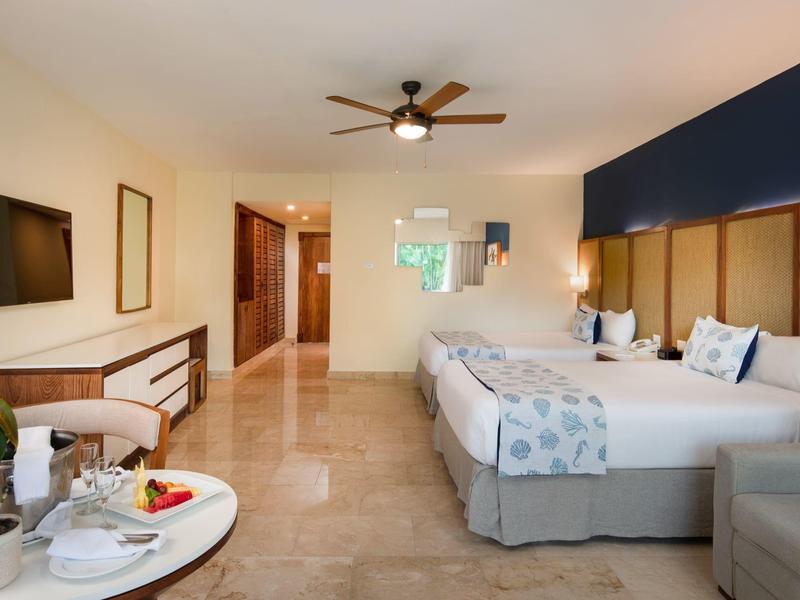 Modernes Hotelzimmer mit zwei Betten, Holzmöbeln und Deckenventilator.