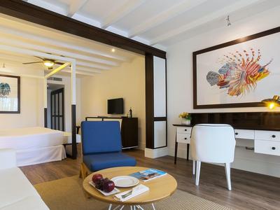 Habitación de hotel moderna con cama, escritorio, televisor y área de estar.