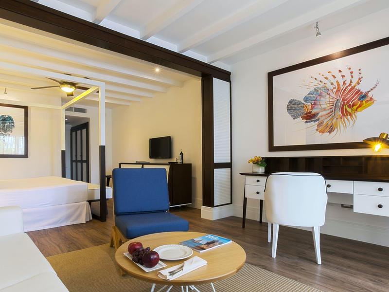 Habitación de hotel moderna con cama, escritorio, televisor y área de estar.