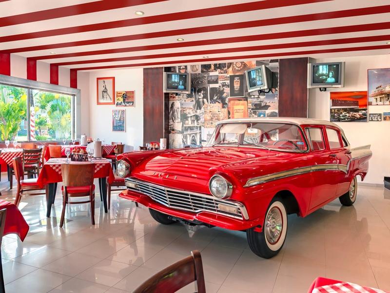 Coche rojo utilizado como decoración en un restaurante con techo a rayas rojas y blancas.