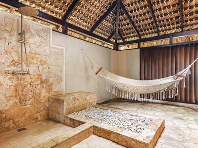 Área exterior luminosa con hamaca, ducha y suelo antideslizante bajo un techo de madera.