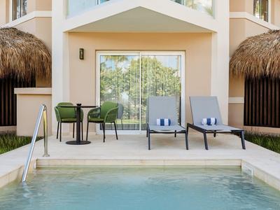 Soukromý bazén s lehátky a stolem před moderní rekreační chatou.