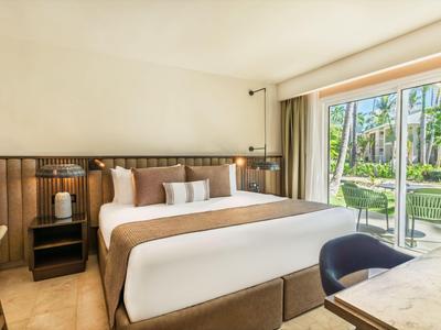 Camera d'hotel moderna con letto grande e vista sul giardino tramite porta scorrevole in vetro.