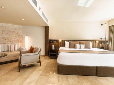 Chambre d'hôtel spacieuse avec grand lit, coin salon et décor en bois chaleureux.