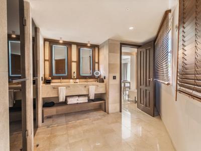 Salle de bain spacieuse d'hôtel avec deux lavabos, grands miroirs et sol en marbre.
