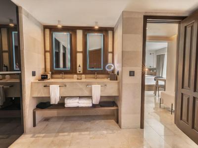 Bagno moderno con doppio lavabo, grandi specchi e ingresso aperto verso la camera da letto.