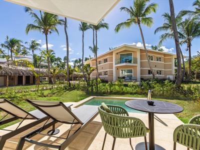 Terrazza con lettini e tavolo con sedie davanti a un hotel con palme