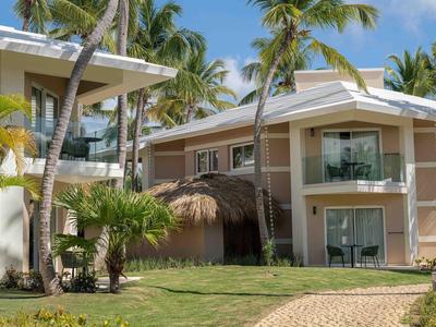 Bungalow moderni dell'hotel con balconi, circondati da palme e prato ben curato.