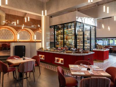 Ristorante moderno con sedie accoglienti e un bar centrale sotto una luce calda.
