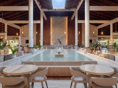 Vista interna di un resort moderno e aperto con vasca centrale e tavoli da pranzo.