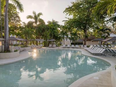 Grande piscina con lettini e palme in un ambiente tropicale dell'hotel al tramonto.