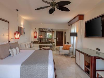 Chambre d'hôtel moderne avec grand lit, ventilateur de plafond et téléviseur à écran plat.