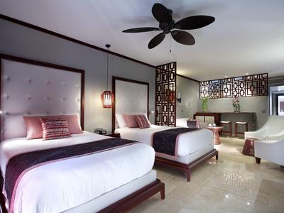 Modernes Hotelzimmer mit zwei Einzelbetten, Deckenventilator und gemütlicher Sitzecke.