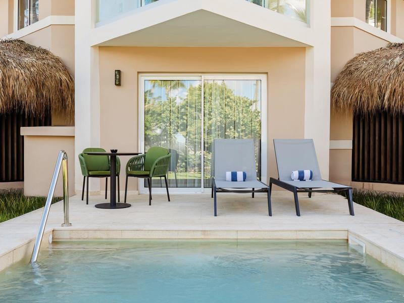 Soukromý bazén s lehátky a stolem před moderní rekreační chatou.