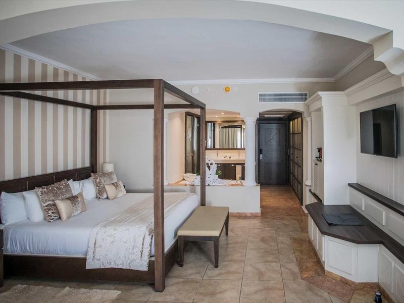 Elegant hotel room with canopy bed, TV, and stylish furnishings.