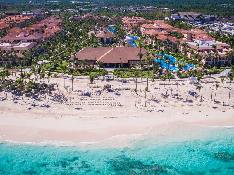 Aerial view of a resort on a white sandy beach with clear turquoise sea water.