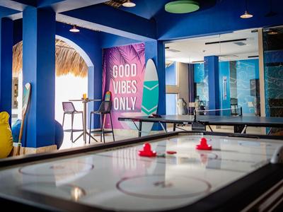 Moderner Spielraum mit blau gestrichenen Wänden, Airhockey-Tisch und bunten Dekorationen.
